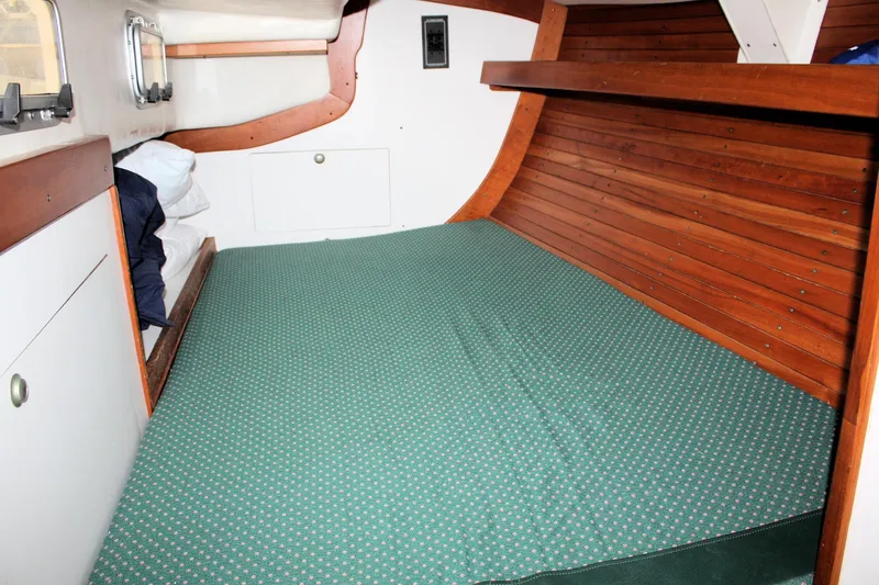 Lola Yacht Photos Pics Cozy cabin interior of 1995 J Boats J/130 with wooden accents and green bedding.