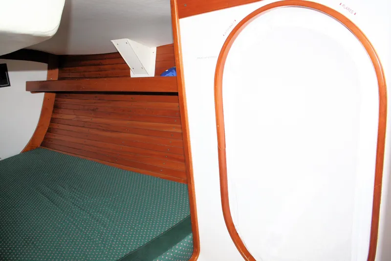 Lola Yacht Photos Pics Interior cabin of 1995 J Boats J/130 with wooden paneling and green bedding.