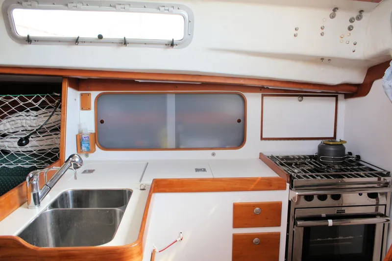 Lola Yacht Photos Pics 1995 J Boats J/130 yacht kitchen with sink, stove, and storage cabinets.