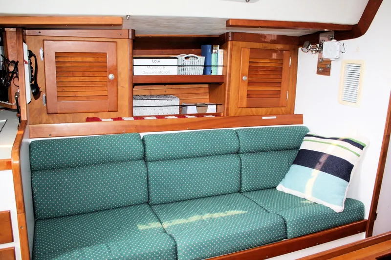 Lola Yacht Photos Pics Interior of 1995 J Boats J/130 with green cushioned seating and wooden cabinets.