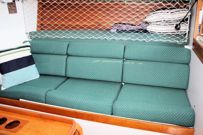 Lola Yacht Photos Pics Interior of 1995 J Boats J/130 with green cushioned seating and storage net.