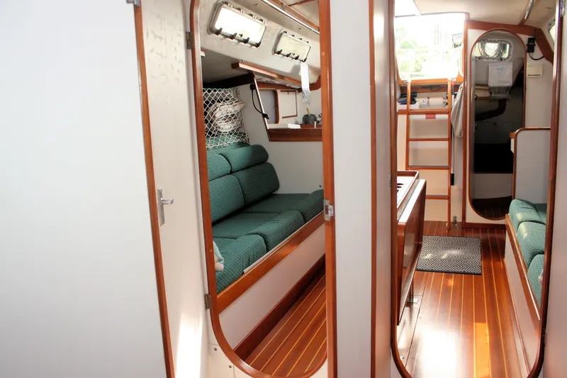Lola Yacht Photos Pics Interior of 1995 J Boats J/130 sailboat with wooden flooring and green seating.
