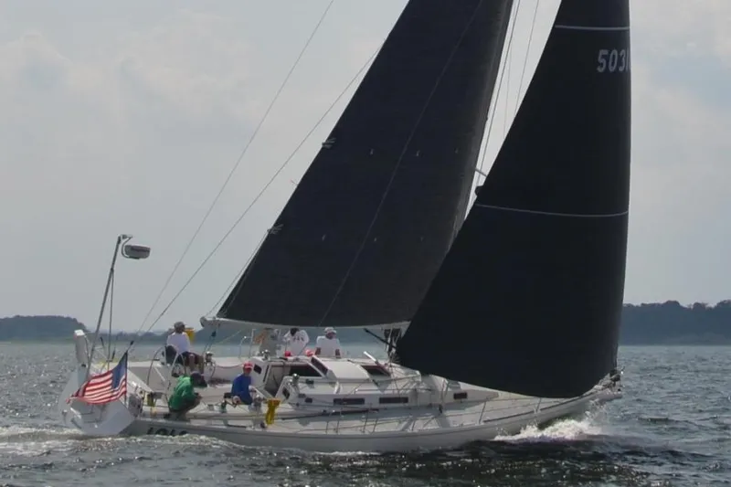 Lola Yacht Photos Pics Sailing yacht J Boats J/130 (1995) with crew on open water, American flag displayed.