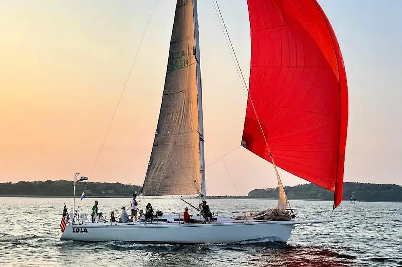 Lola Yacht Photos Pics Sailing yacht J/130 from 1995 with red spinnaker at sunset on open water.