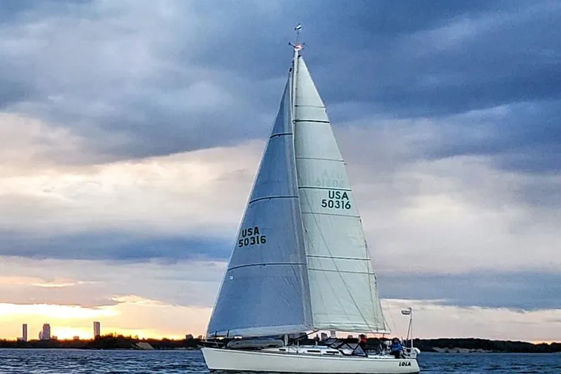 Lola Yacht Photos Pics Sailboat J/130 from 1995 on water at sunset, dramatic sky background.
