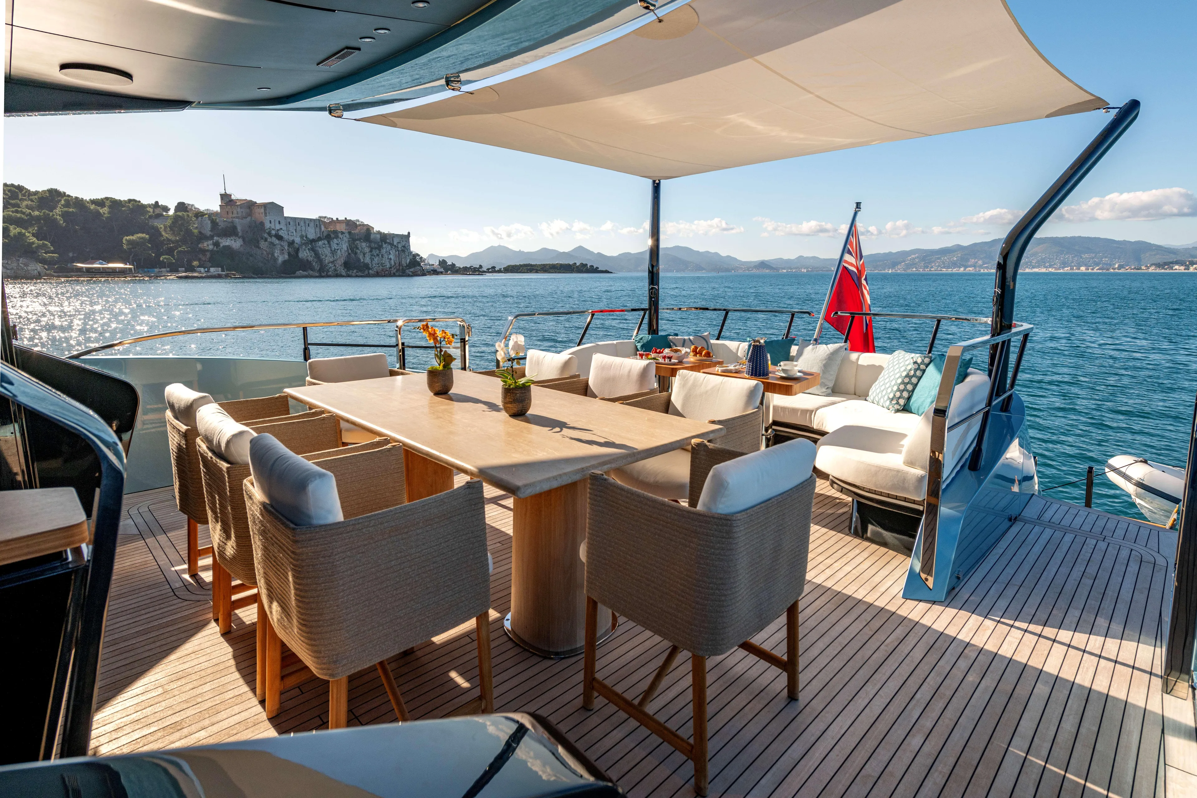Delfina Yacht Photos Pics Luxurious 2024 Mangusta 104 REV yacht deck with elegant dining area and scenic ocean view.