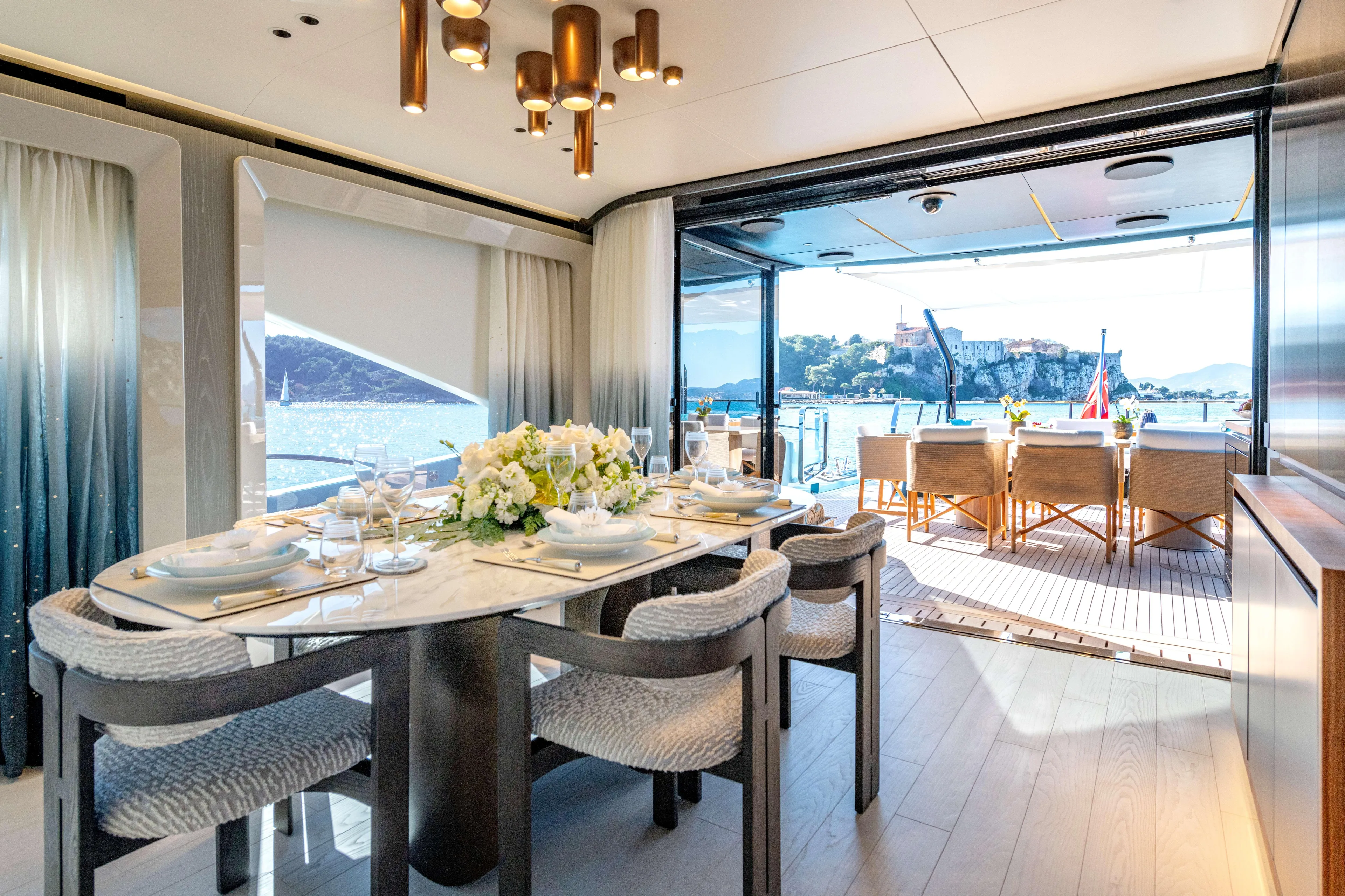 Delfina Yacht Photos Pics Luxurious dining area on 2024 Mangusta 104 REV yacht with ocean view.