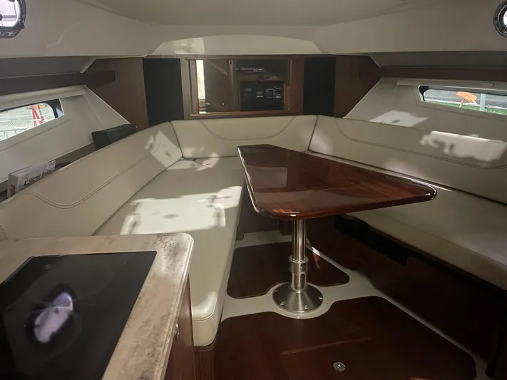Sea Hawk Yacht Photos Pics 2020 Pursuit OS 355 Offshore cabin interior with leather seating and wooden table.