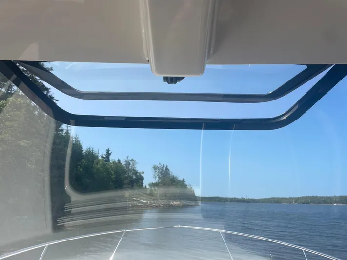 Sea Hawk Yacht Photos Pics 2020 Pursuit OS 355 Offshore boat view through windshield, cruising on a serene lake.