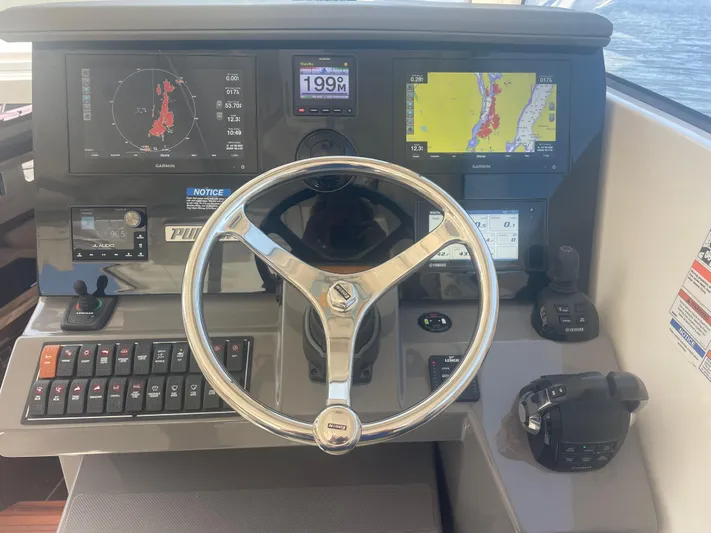 Sea Hawk Yacht Photos Pics Control panel of 2020 Pursuit OS 355 Offshore boat with navigation displays and steering wheel.