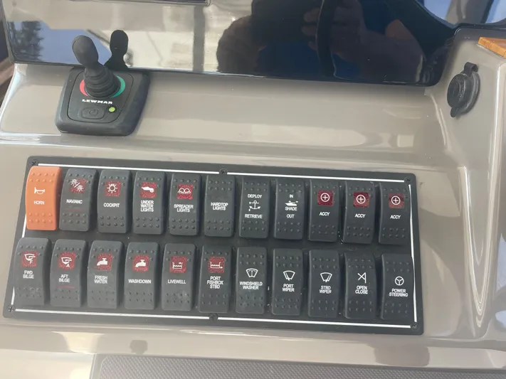 Sea Hawk Yacht Photos Pics Control panel of a 2020 Pursuit OS 355 Offshore boat with various switches and joystick.