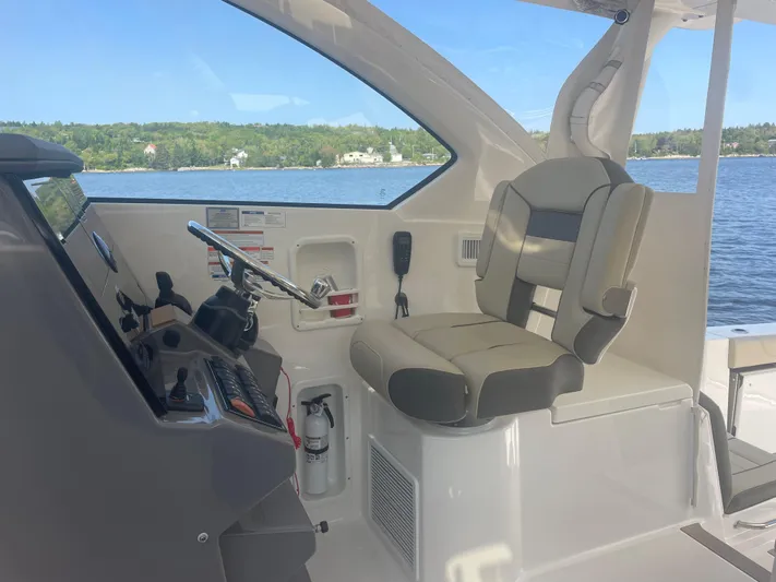 Sea Hawk Yacht Photos Pics 2020 Pursuit OS 355 Offshore boat interior with helm and seating, overlooking serene water.