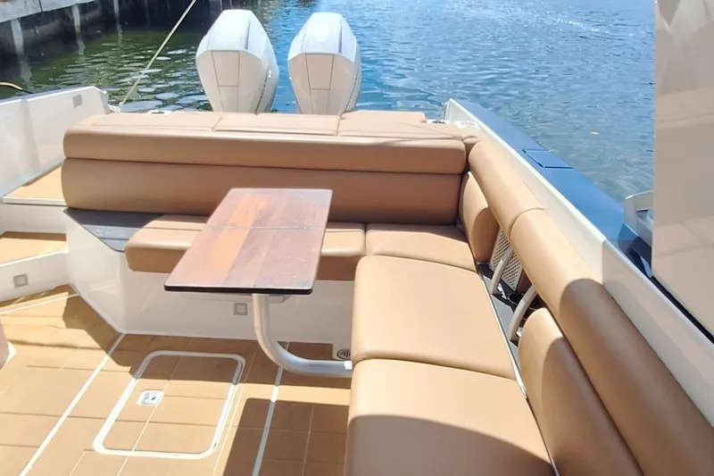  Yacht Photos Pics 2021 Aviara AV32 OB boat interior with tan seating and wooden table, docked by the water.