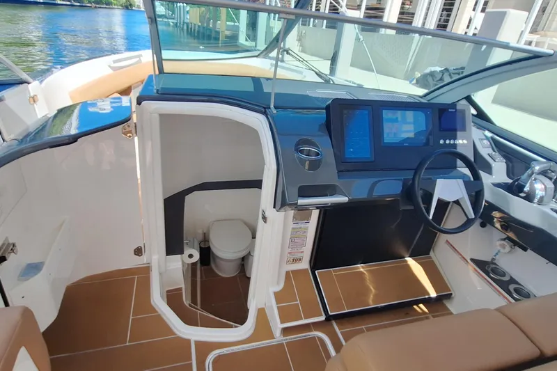  Yacht Photos Pics 2021 Aviara AV32 OB boat interior with helm, digital displays, and compact restroom.
