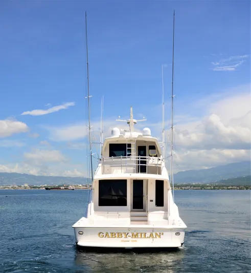 Gabby Millan 2 Yacht Photos Pics 2003 Bertram 67 Convertible yacht on calm waters with clear sky.