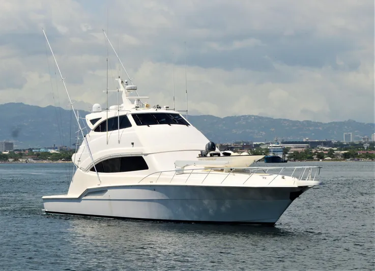 Gabby Millan 2 Yacht Photos Pics 2003 Bertram 67 Convertible yacht on calm waters with cityscape background.