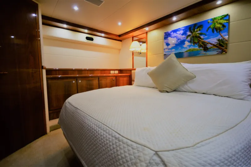 Gabby Millan 2 Yacht Photos Pics Luxurious bedroom interior of 2003 Bertram 67 Convertible yacht with cozy bed and tropical artwork.