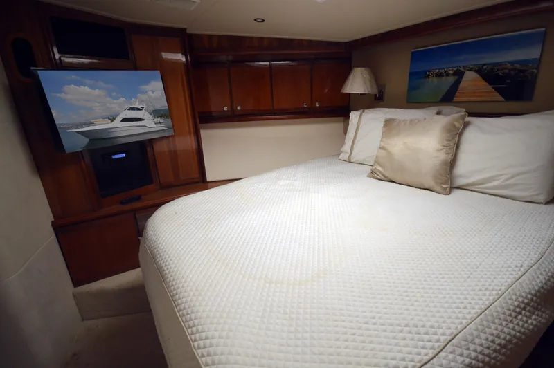 Gabby Millan 2 Yacht Photos Pics Luxurious bedroom interior of 2003 Bertram 67 Convertible yacht with TV and wooden cabinets.