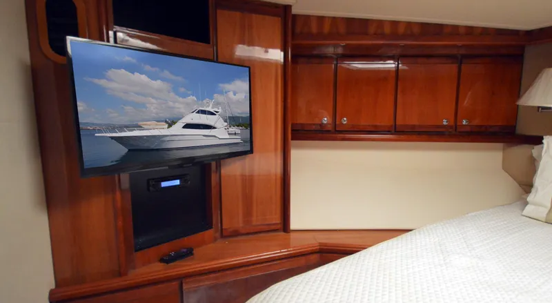 Gabby Millan 2 Yacht Photos Pics Luxurious cabin interior of 2003 Bertram 67 Convertible yacht with TV and wooden cabinets.