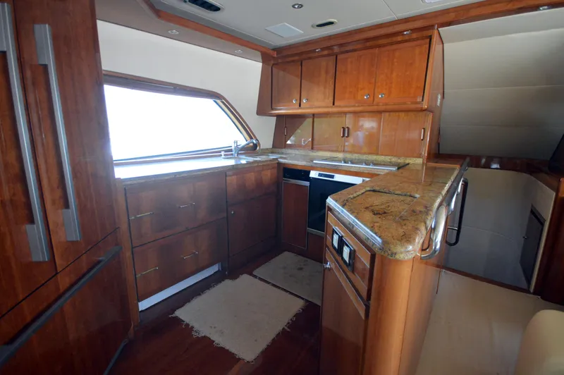 Gabby Millan 2 Yacht Photos Pics 2003 Bertram 67 Convertible yacht kitchen with wooden cabinets and granite countertops.