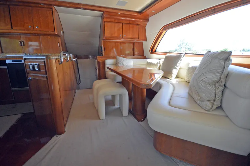Gabby Millan 2 Yacht Photos Pics Luxurious interior of 2003 Bertram 67 Convertible yacht with wooden cabinetry and white seating.