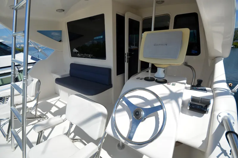 Gabby Millan 2 Yacht Photos Pics 2003 Bertram 67 Convertible yacht helm station with seating and navigation equipment.