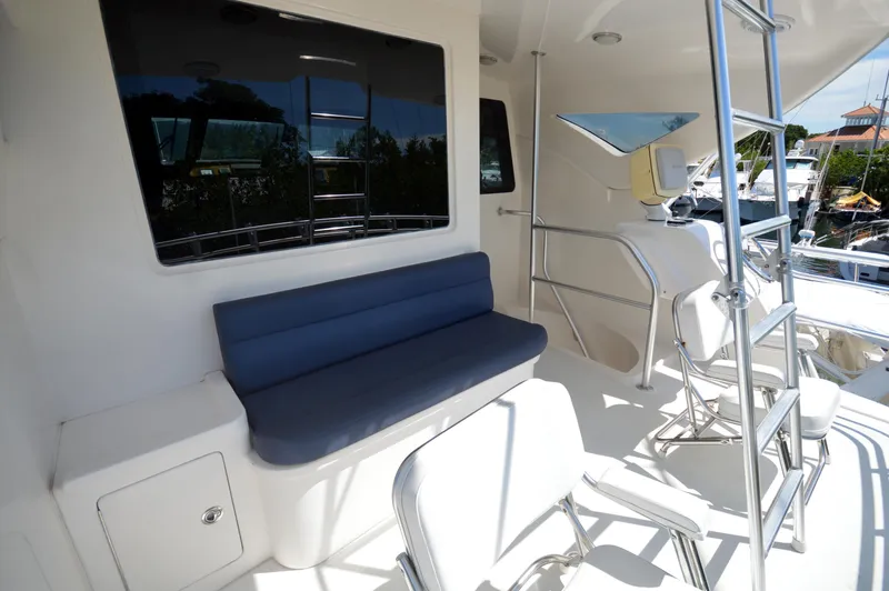 Gabby Millan 2 Yacht Photos Pics 2003 Bertram 67 Convertible yacht seating area with blue cushioned bench and white chairs.