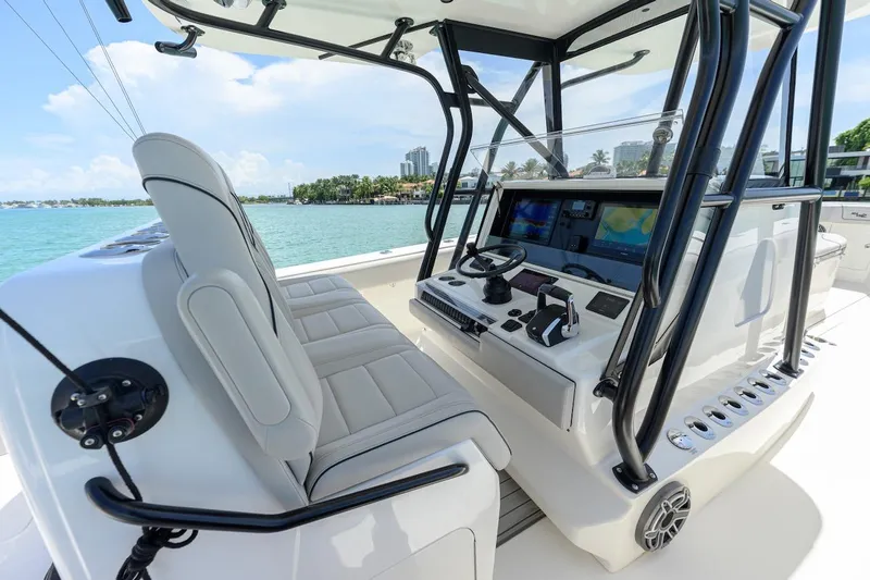  Yacht Photos Pics 2023 SeaVee 370Z boat cockpit with modern controls and seating, overlooking a scenic waterfront.