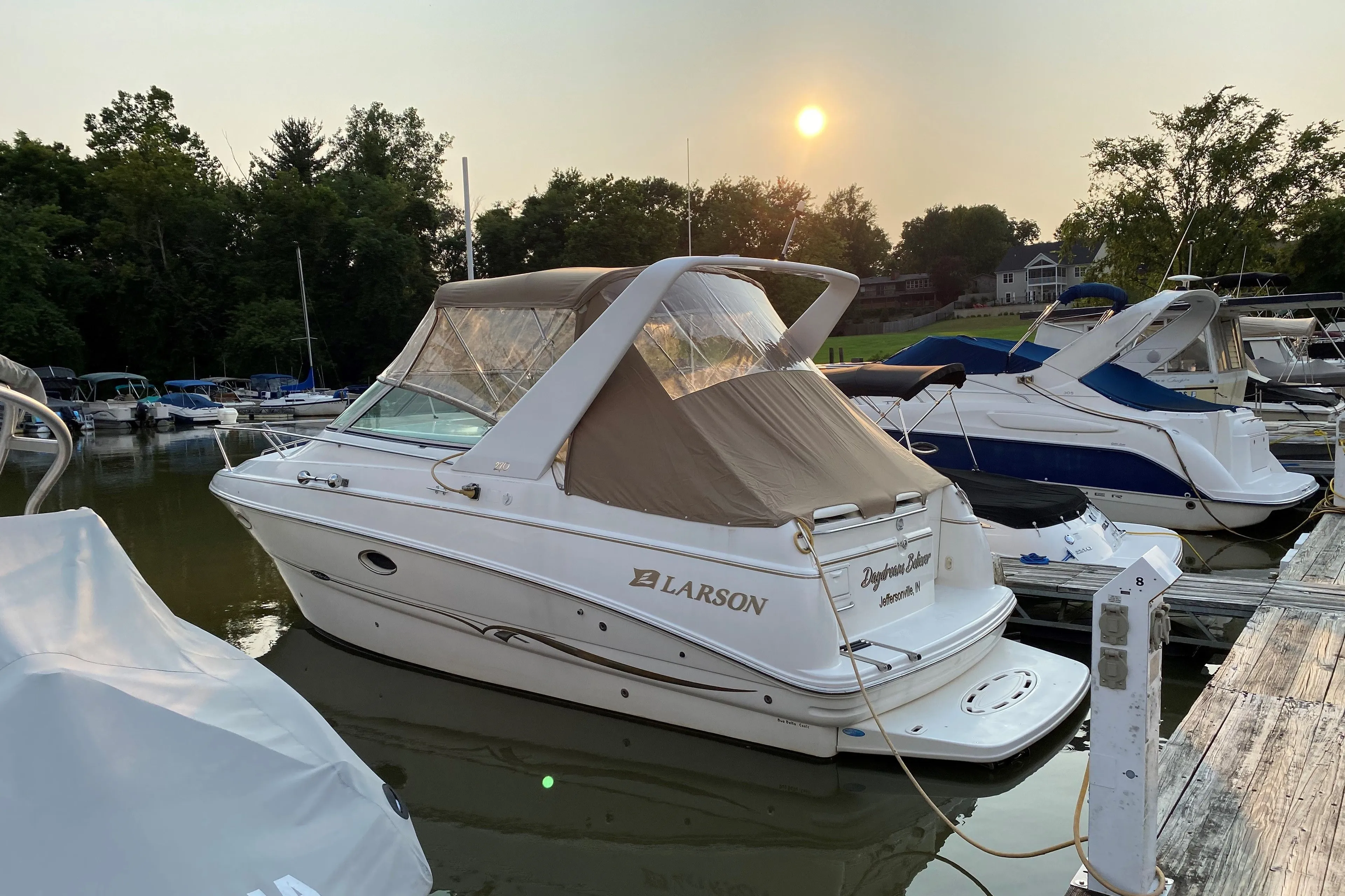 2001 Larson Cabrio 270 boat docked at marina during sunset.