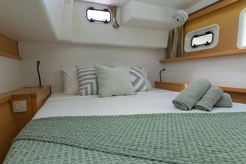 Miss Summer Yacht Photos Pics Cozy bedroom in 2014 Lagoon 450 yacht with neatly arranged bed and porthole windows.