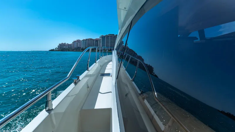 Next To Sell Yacht Photos Pics 2005 Marquis 59 yacht cruising on clear blue waters near coastal buildings.