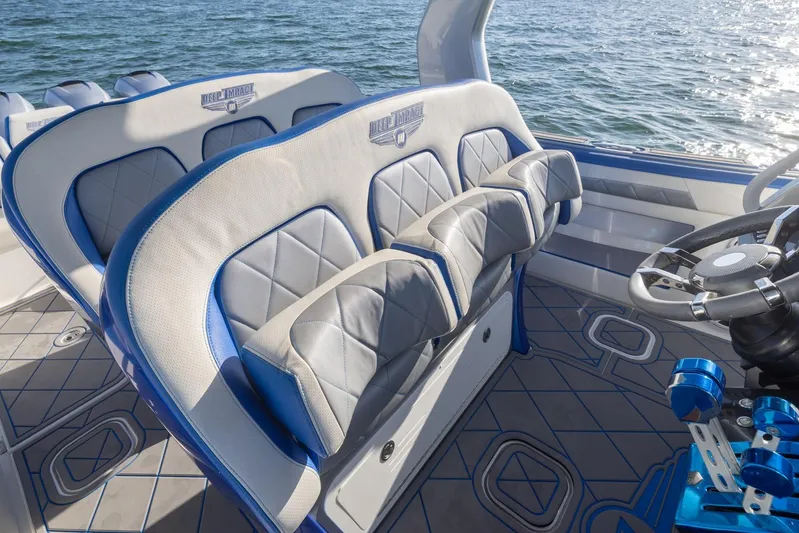 Loan Shark II Yacht Photos Pics 2019 Deep Impact 399 Sport boat interior with blue and gray seating, steering wheel, and ocean view.