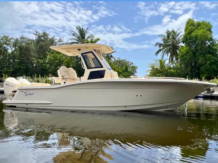  Yacht Photos Pics 2026 Scout 260 LXF boat on calm water, surrounded by lush greenery and clear skies.