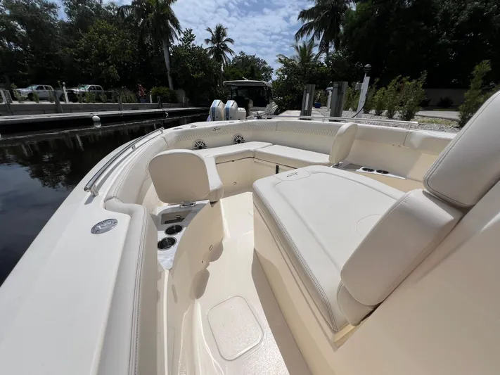  Yacht Photos Pics 2026 Scout 260 LXF boat interior with luxurious seating and cup holders, docked near lush greenery.