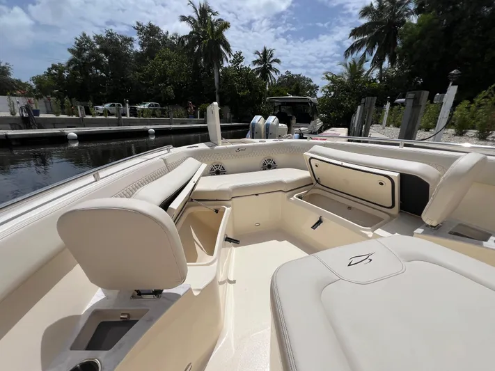  Yacht Photos Pics 2026 Scout 260 LXF boat interior with seating and storage, docked near lush greenery.