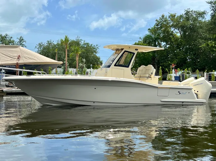  Yacht Photos Pics 2026 Scout 260 LXF boat on calm water, surrounded by trees and clear sky.