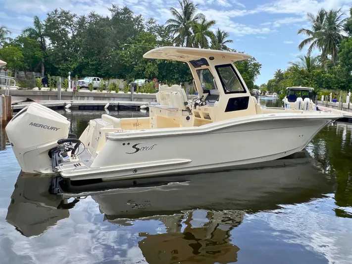  Yacht Photos Pics 2026 Scout 260 LXF boat docked on calm water, surrounded by lush greenery and palm trees.