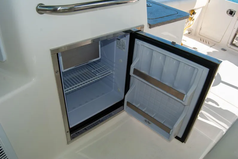  Yacht Photos Pics Open refrigerator on 2021 Boston Whaler 345 Conquest boat, showcasing interior storage space.