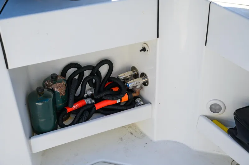  Yacht Photos Pics Storage compartment in a 2021 Ocean Sport 26/27 boat with hoses and gas canisters.