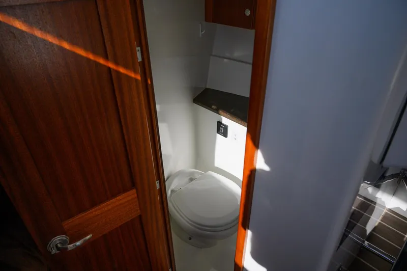  Yacht Photos Pics Compact bathroom in 2021 Ocean Sport 26/27 boat with wooden door and modern fixtures.