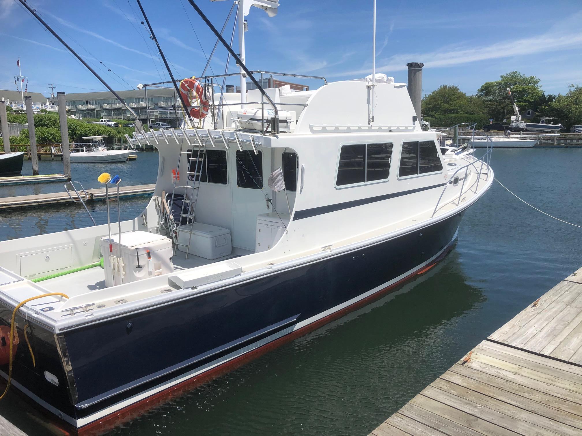 2003 Wesmac Flybridge boat docked in a marina under clear skies.