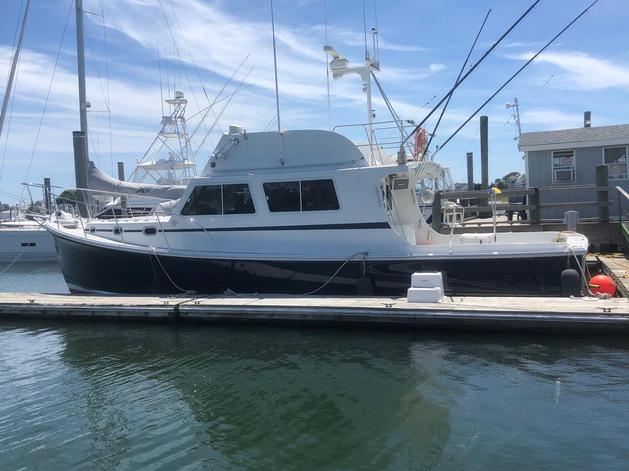 2003 Wesmac Flybridge boat docked at marina under clear blue sky.