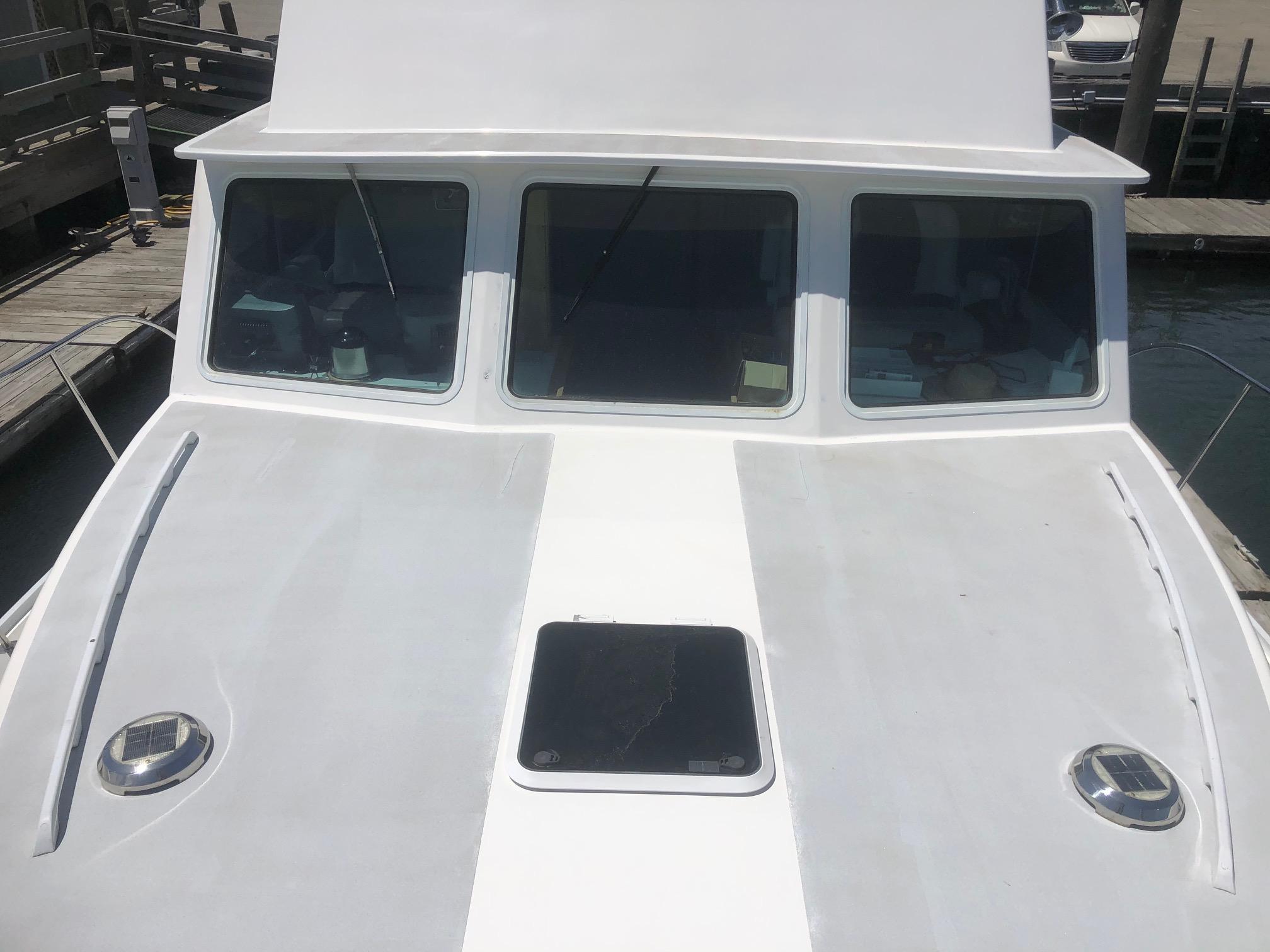 2003 Wesmac Flybridge boat with white deck and windows at a marina.