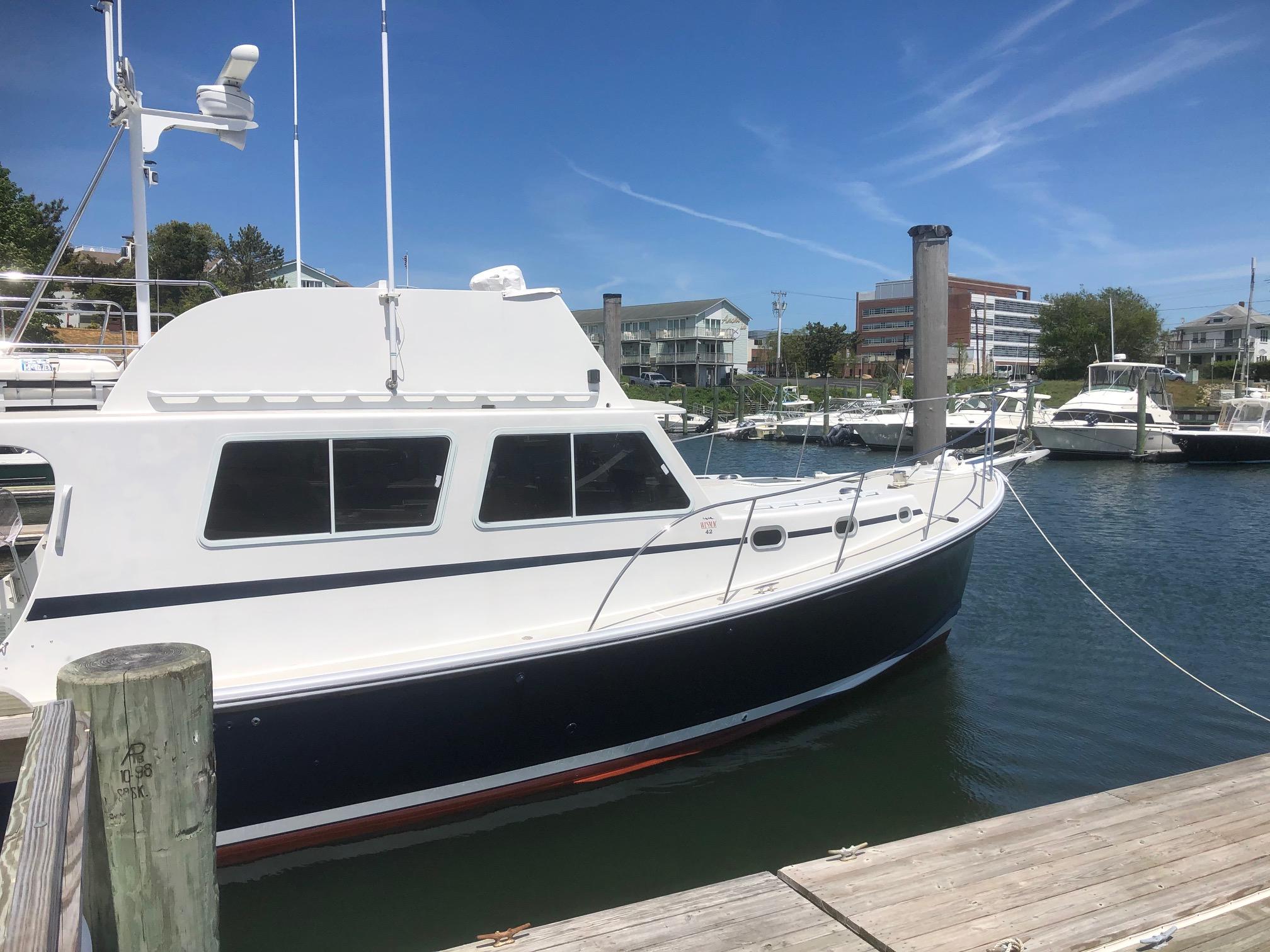 2003 Wesmac Flybridge boat docked in a marina under clear blue skies.