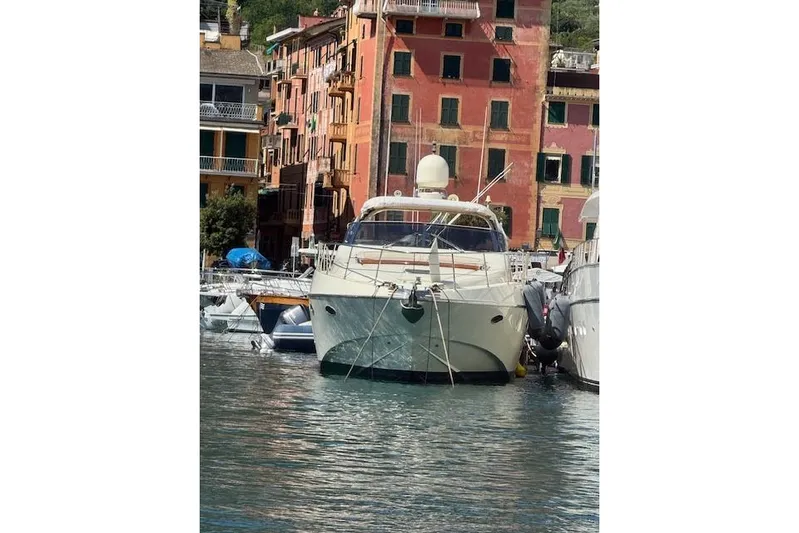  Yacht Photos Pics Luxury yacht Riva 59 Mercurius 2002 docked in picturesque harbor with colorful buildings.