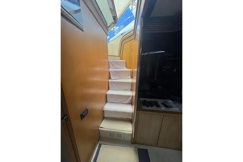  Yacht Photos Pics Interior staircase of 2002 Riva 59 Mercurius yacht, featuring wooden paneling and carpeted steps.