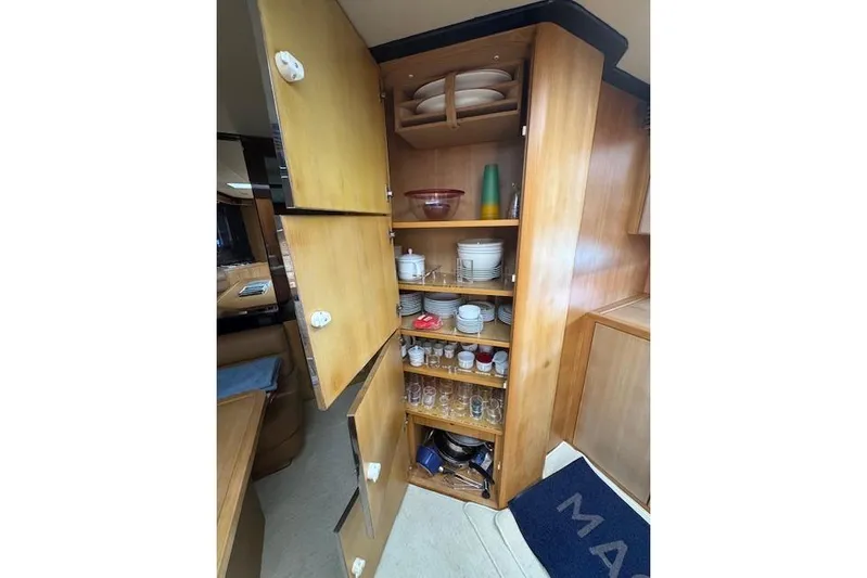  Yacht Photos Pics Wooden cabinet with open doors displaying dishes and glassware on a 2002 Riva 59 Mercurius yacht.