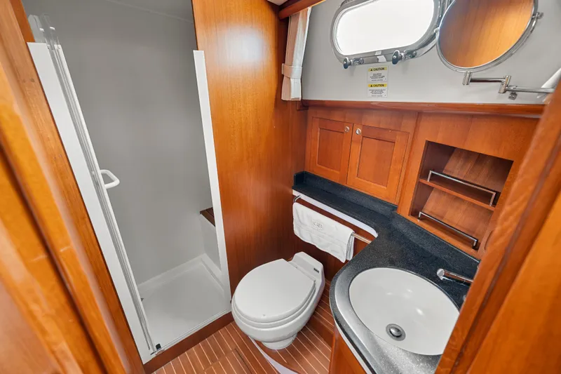 Whole Life Yacht Photos Pics Luxurious 2011 Grand Banks 46 Eastbay SX yacht bathroom with shower, sink, and wooden cabinetry.