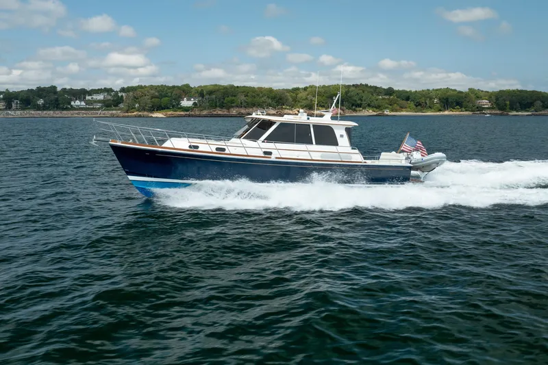 Whole Life Yacht Photos Pics 2011 Grand Banks 46 Eastbay SX cruising on open water, scenic shoreline in background.