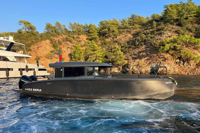  Yacht Photos Pics 2021 XO EXPLORER 10S boat cruising near rocky shoreline with trees.